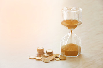 Hourglass and coins on table