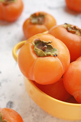 Pot with ripe persimmons on light background, closeup