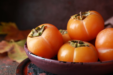 Plate with ripe persimmons on table, closeup