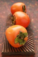 Board with ripe persimmons on grunge background