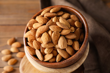 Bowls with tasty almonds on wooden table, closeup