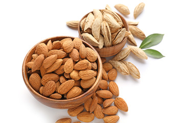 Bowls with tasty almonds on white background