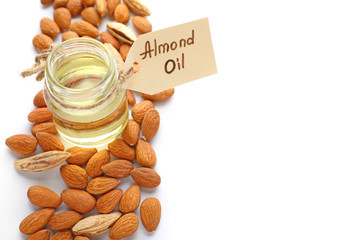 Tasty almond oil with nuts on white background