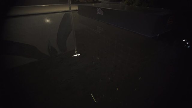 Light reflections in a pool of water at night at business district in Paris, slow steadicam movement fish eye lens wide shot. Futuristic modern building. 4K UHD.