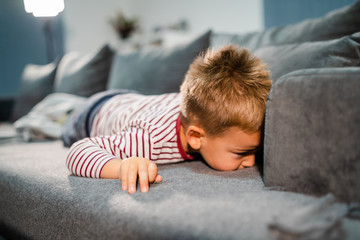 Three years old boy small little kid child playing on the bed having fun laying about to sleep