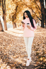 Beautiful woman drink coffee, using phone and walking in the park.