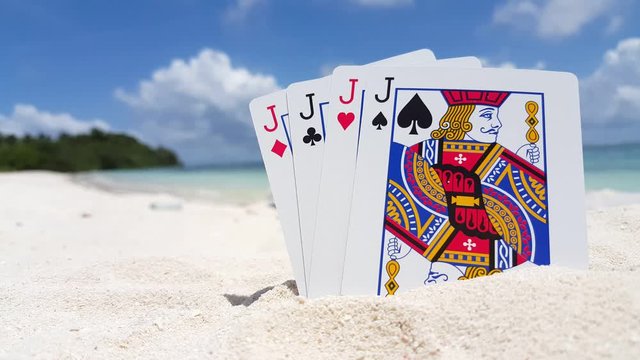four of a kind, playing cards on the white sand beach. Four jacks, poker