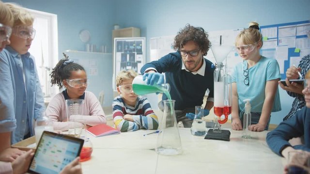 Elementary School Science / Chemistry Classroom: Enthusiastic Teacher Shows Funny Chemical Reaction Experiment to Group of Children. Mixing Chemicals in Beaker so they Shoot Foam (Elephant Toothpaste)