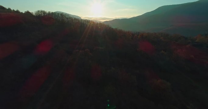 Levee drone aerial at sunrise with hills and mountains in Hungary, Hasznos. Sun rises behind the hills, reflections on the water.