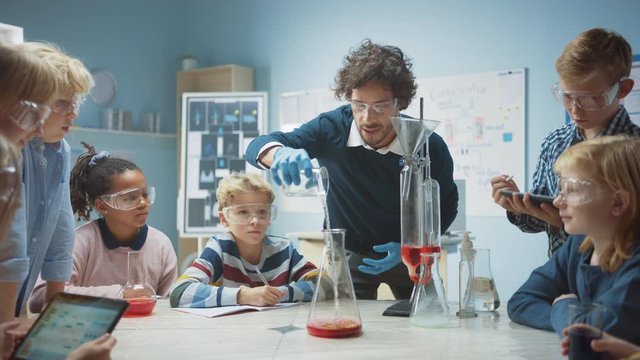 Elementary School Chemistry Classroom: Enthusiastic Teacher Teaches Diverse Group of Children Shows Science Reaction Experiment by Mixing Chemicals in Beaker so they Shoot Foam (Elephant Toothpaste)