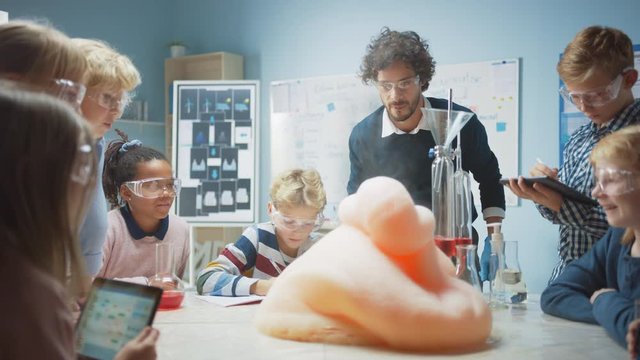 Elementary School Chemistry Classroom: Enthusiastic Teacher Teaches Diverse Group of Children Shows Science Reaction Experiment by Mixing Chemicals in Beaker so they Shoot Foam (Elephant Toothpaste)