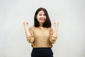 happy cheerful Asian business woman smiling against grey wall background 