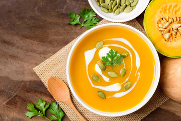 Butternut squash soup with pumpkin seed and fresh butternut squash on wooden background