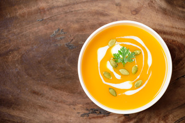 Butternut squash soup with pumpkin seed in a bowl on wooden background