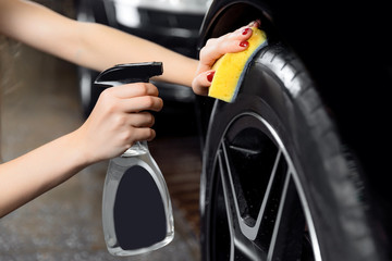Car wash service, detailing using spray and sponge to wipe black tire