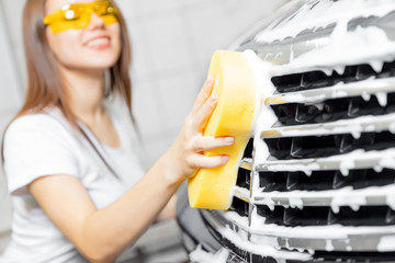 Hand woman car wash foam with yellow sponge headlights