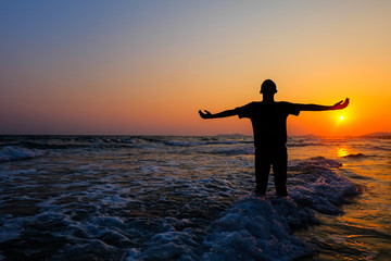 Fototapeta premium A silhouette of a person relaxing on the sea.Happiness after completion of work.sunset and sunrise.