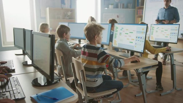 Elementary School Science Classroom: Teacher Educates Smart Little Schoolchildren who Work on Personal Computers, Learn Programming Language for Software Coding.Schoolchildren Getting Modern Education