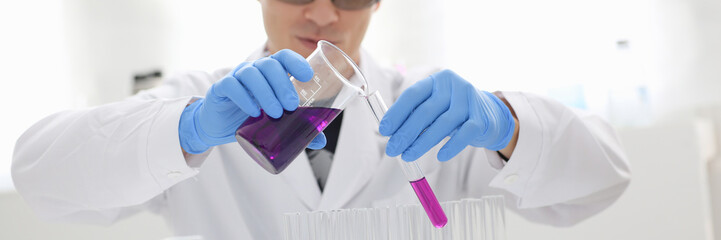 A male chemist holds test tube of glass