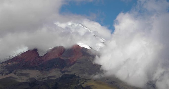 Volcano Cotopaxi in Ecuador peeking through clouds moving in real time, mountain landscape in the Andes