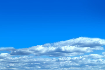 White clouds on a background of deep blue sky. Place for text from above.