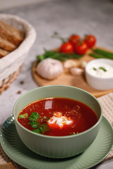 Beetroot soup with sour cream and herbs in a plate, close-up. Tasty and hearty dinner, borsch with vegetables. Still life
