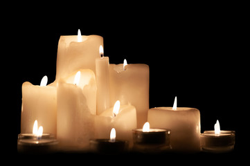 Composition burning candles close-up. Isolated on black. Melted wax candles of different shapes.