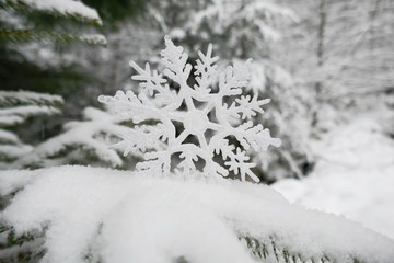 Snowflake decor close-up in the snow in a snowy winter forest.Winter time.Winter holidays background
