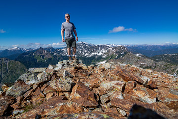 Adventurous man standing on top of a mountain.