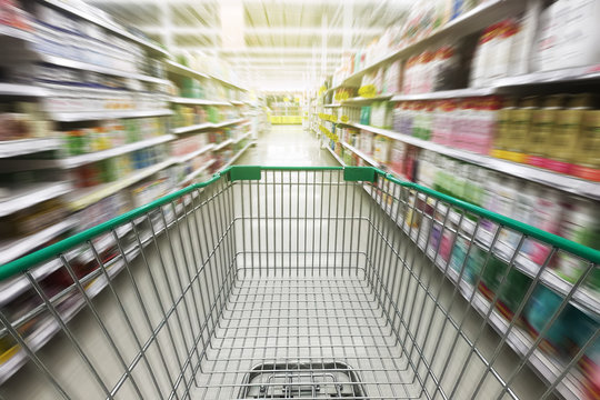 Shopping cart or trolley in supermarket aisle with empty  during buying food or product in grocery store.Empty cart with abstract blur supermarket discount store.