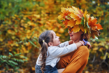 Portrait of a little girl and mother in the autumn Park, a girl with a wreath of maple leaves .