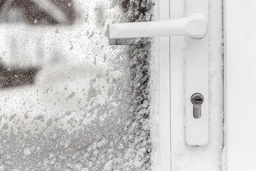 The white front door is covered with snow after a blizzard.