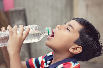 Indian boy drink water from a plastic bottle