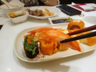 Japanese food style, Selective focus of chopsticks holding crab stick on sushi as a background in restaurant, Ready to eat or serve