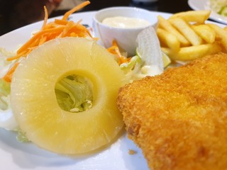 Selective focus of pineapple mixed vegetable salad with dory steak and french fries on white plate in restaurant ready to eat or serve