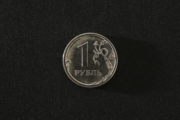 One Russsian rouble coin on a black blurred shiny background. Metal Russian money. Top view. Closeup. Copy space. Hard side light
