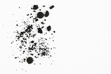 Black round crushed pills on white background. Broken and squashed activated carbon tablets. Medicine concept. Copy space