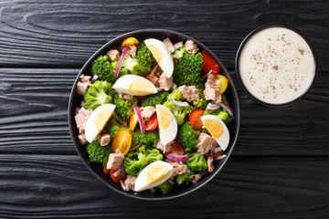 Healthy diet food salad with tuna, broccoli, tomatoes, onions and eggs close-up in a plate. Horizontal top view