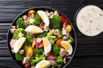 American traditional salad with tuna, broccoli, tomatoes, onions and eggs close-up in a plate. Horizontal top view