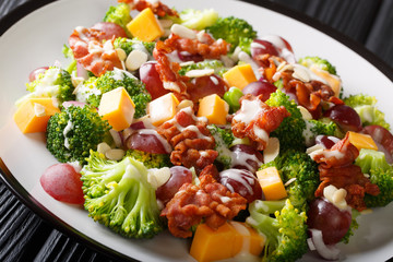 Broccoli salad with cheddar cheese, grapes, bacon, almonds and onions close-up in a plate. horizontal