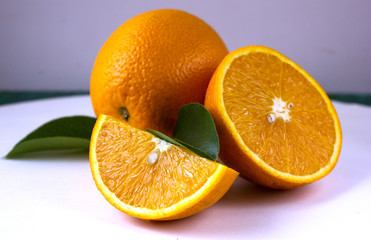Orange fruit with orange slices and leaves on white  background.