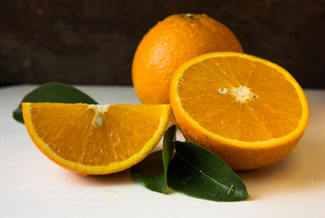 Orange fruit with orange slices and leaves on darck background.