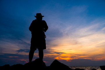 tourist with backpack of freedom on sand beach in silhouette of asian young woman relaxing, standing looking sunset scene in summer sky outdoor. journey trip outdoors in summer concept