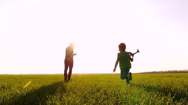 Happy family: dad and son play running through a green meadow, launching a plane into the sky. Traveling.