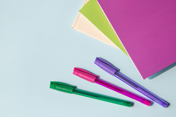 Office supplies or stationery. Multi-colored pens and notebooks. Top view, with copy space.