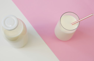 bottle of organic milk and glass of milk on the pink and white background with copy space for text. Dairy products background.  Flat lay. Top view.