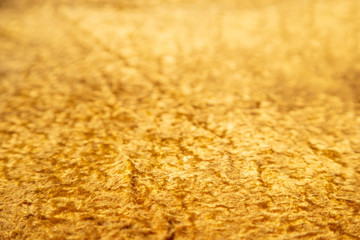 Golden background of shining velvet with defocus or bokeh