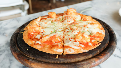 Tom Yum Kung pizza with shrimp on top in wooden plate