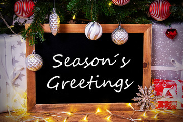 Obraz na płótnie Canvas Blackboard With English Text Seasons Greetings. Christmas Tree With Ball, Gifts And Fairy Lights