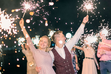 Beautiful wedding finale, the bride and groom and their guests lit sparklers in the street